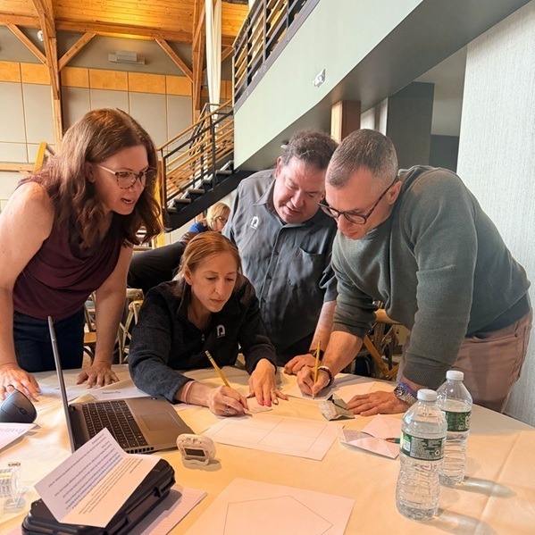 A group of four Nysernet staff gather around a workspace to solve a problem together.