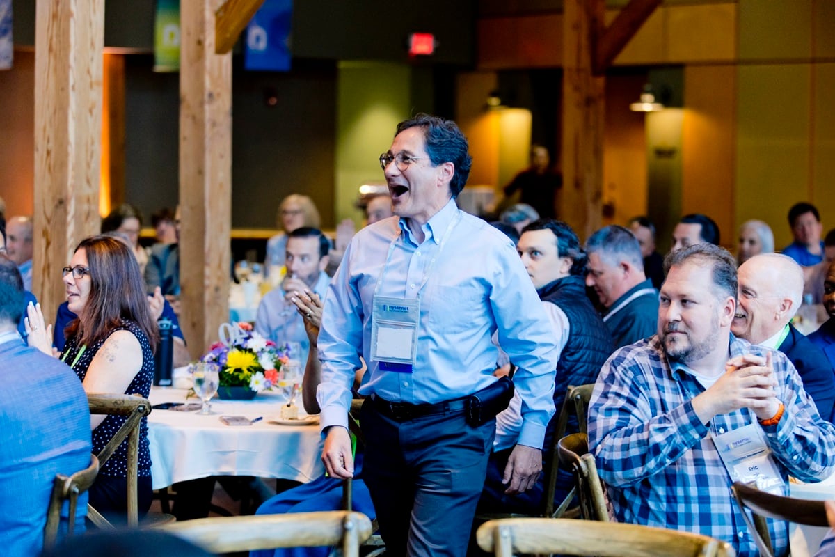 Nysernet member excitedly walking through a sea of banquet tables filled with other Nysernet members.