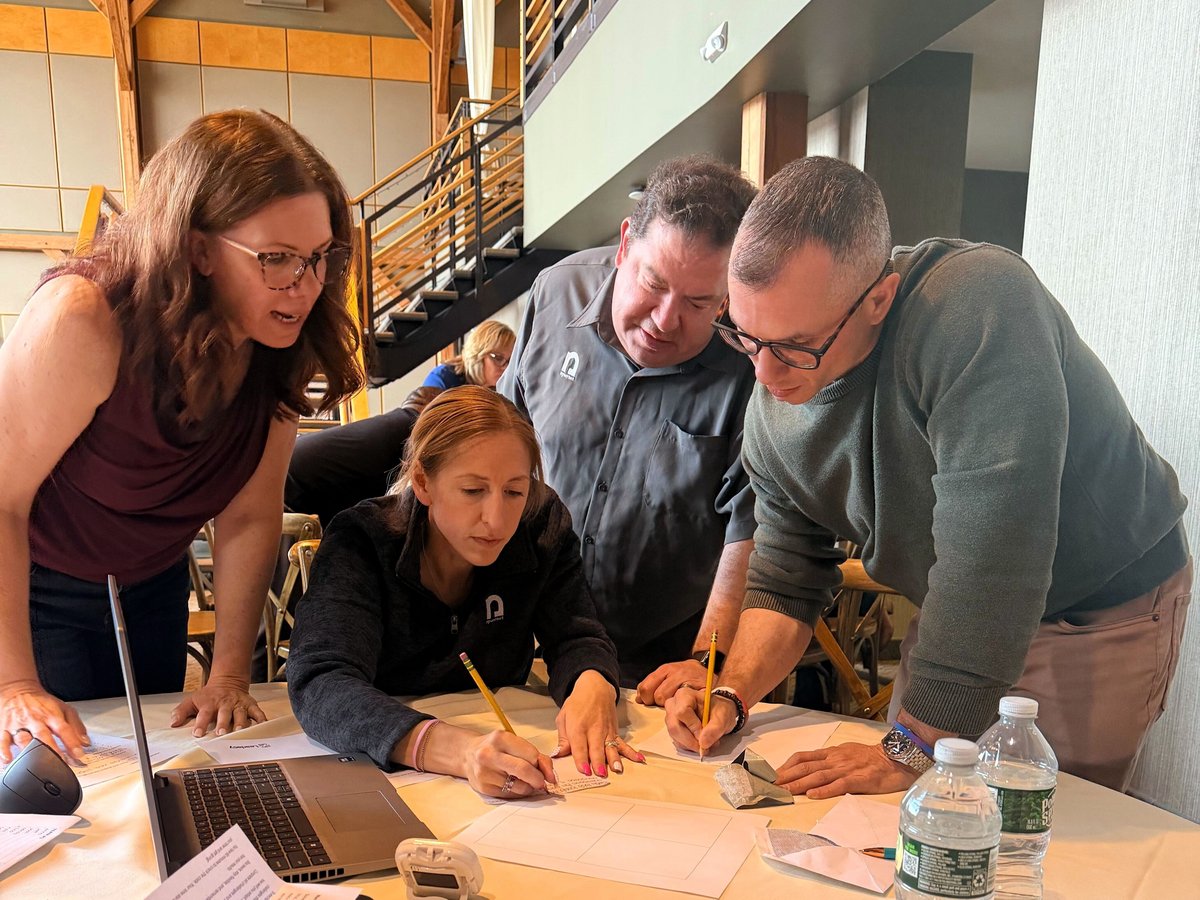 A group of four Nysernet staff gather around a workspace to solve a problem together.